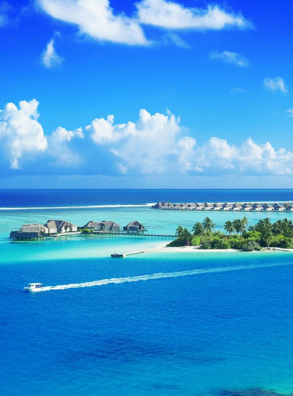 Crystal clear waters surround a luxurious Maldives resort under a bright blue sky.